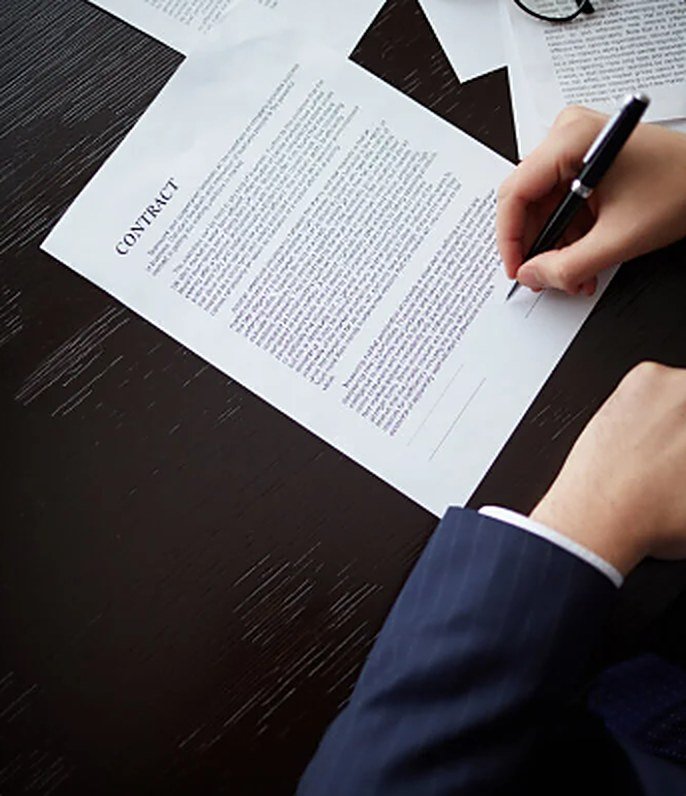 Hands signing a contract with a pen on a desk